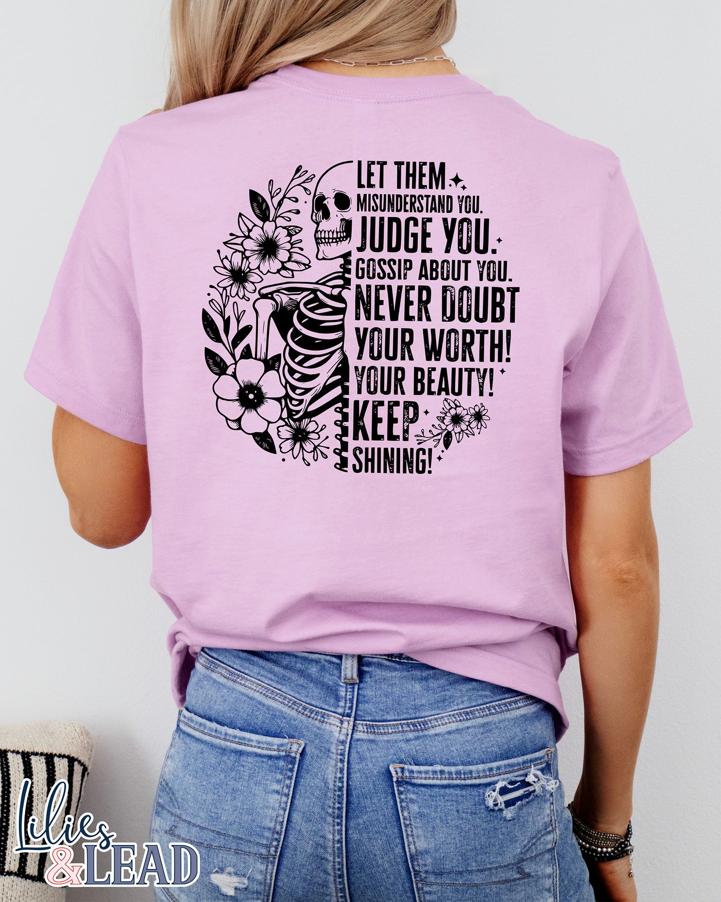 Lilac short sleeve tee with black skeleton and florals and the saying "Let them misunderstand you, judge you, gossip about you. Never doubt your worth! Your Beauty! Keep Shining!"