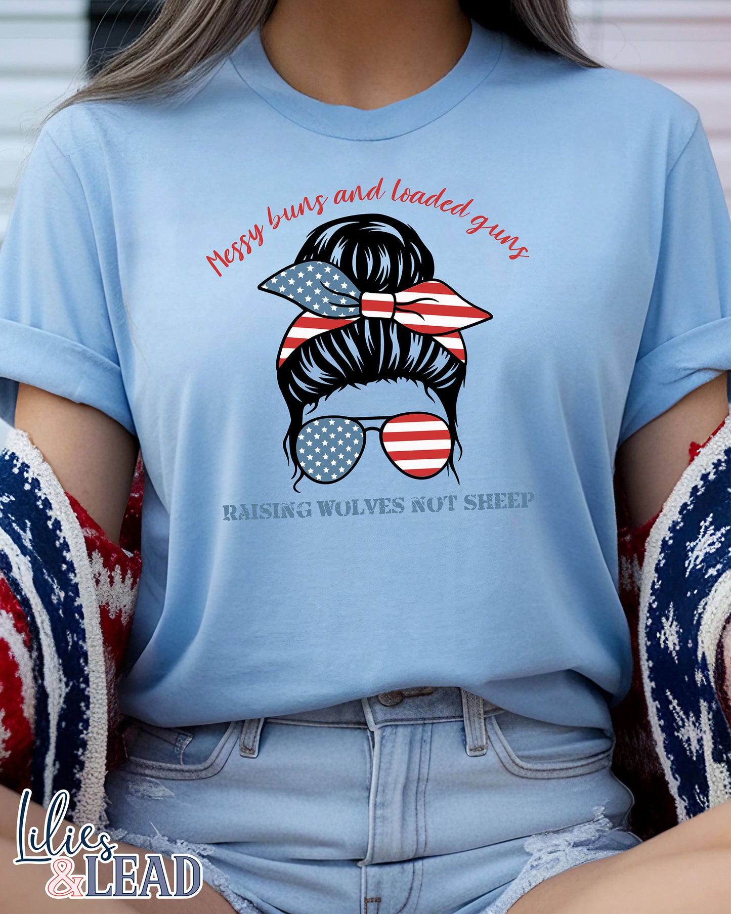 light blue  tee shirt  on model with messy buns design wearing patriotic bandana and sunglasses featuring the phrase Messy uns and loaded guns raising wolves not sheep