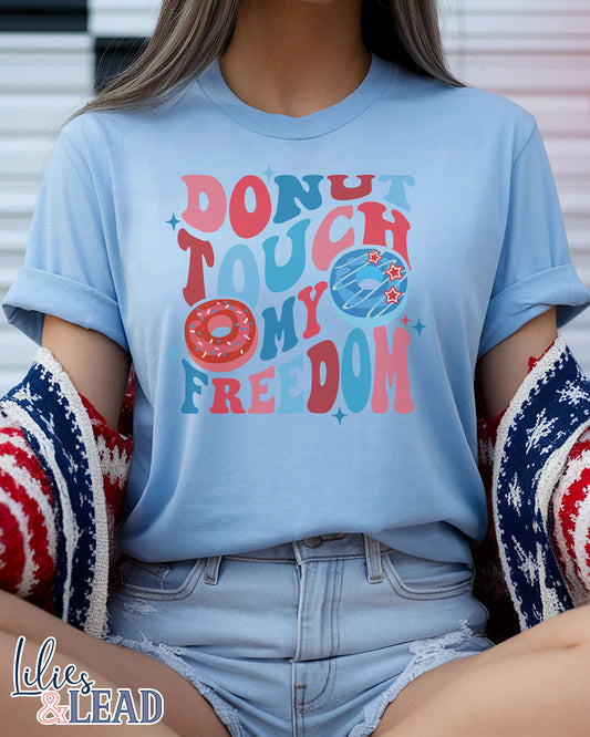 Baby blue tee with Donut Touch My Freedom printed in red, white, and blue with donut graphics.