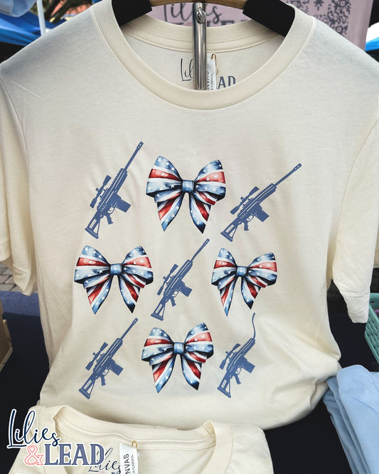 Tee shirt with patriotic bows and rifle detail hanging on display
