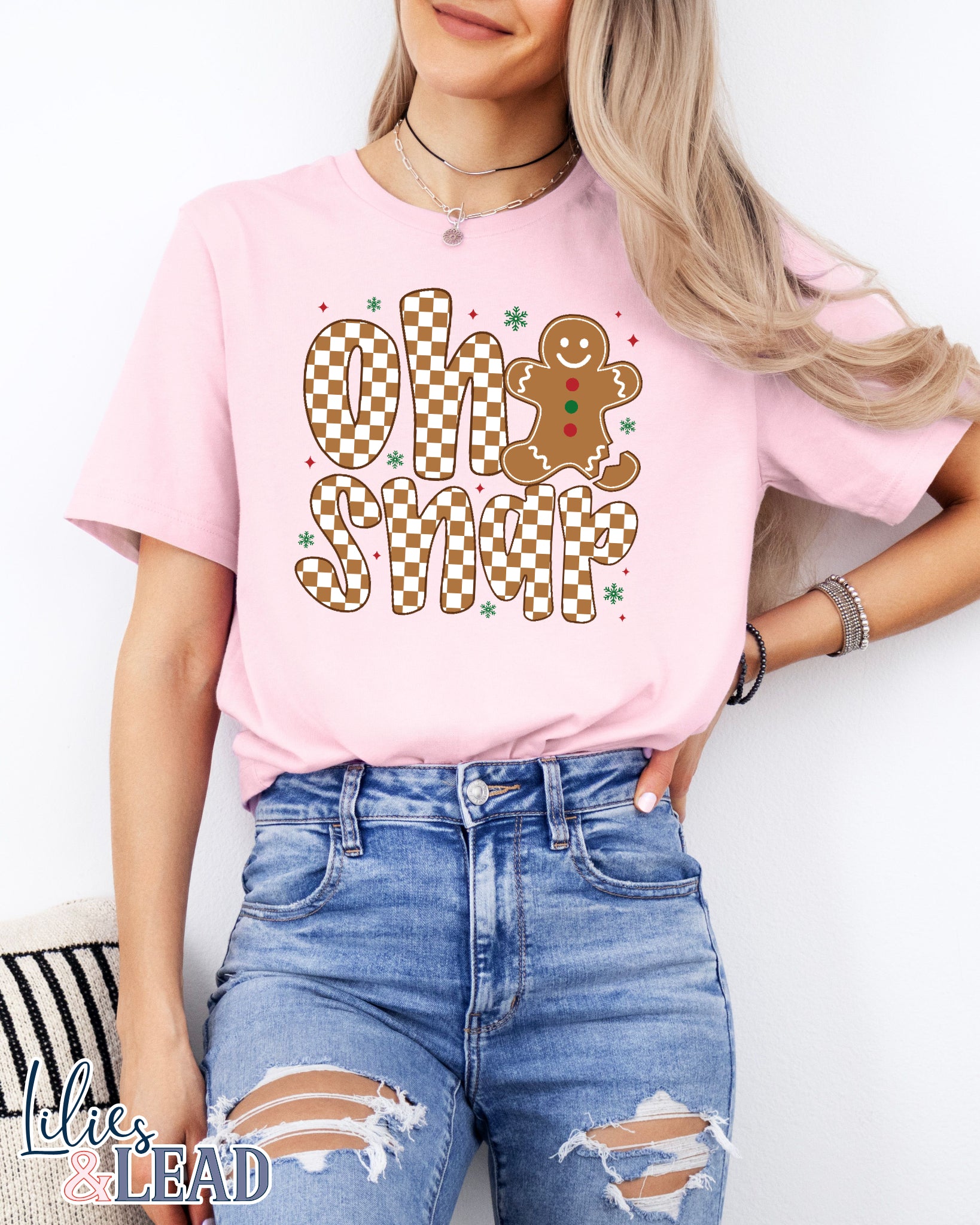 Person wearing a pink t-shirt with 'Oh Snap' and gingerbread design, standing against a white background.