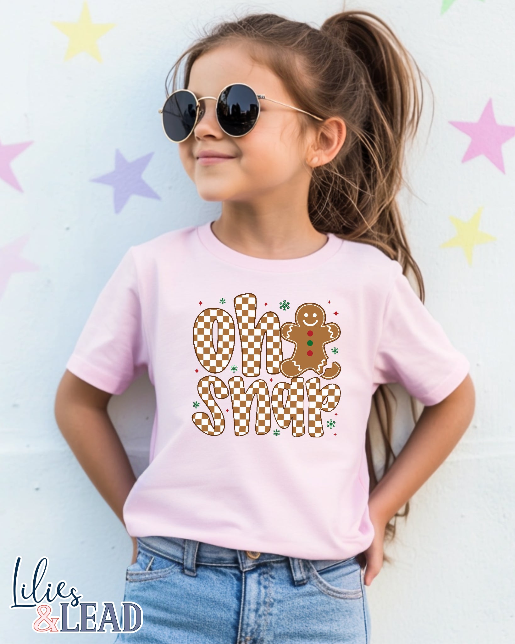 Child wearing a pink t-shirt with 'Oh Snap' design, standing against a star-patterned background.