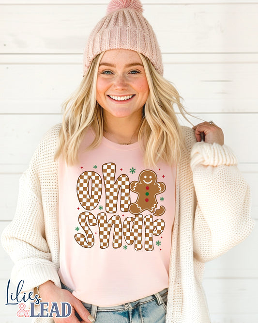Woman wearing a pink shirt with 'Oh Snap' gingerbread design and a pink beanie against a white background.